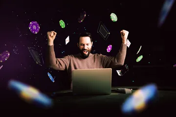 A man celebrating a winning moment on his laptop while gaming symbols float around him, capturing the excitement of CROWNBD games.